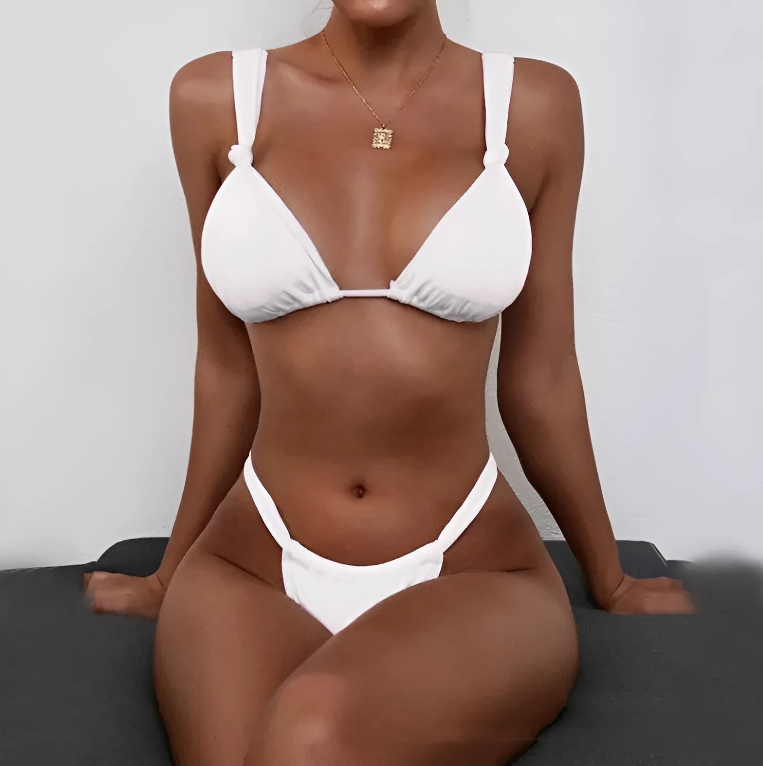 Women's pink bikini with a knotted front and pleated split straps, laid flat.