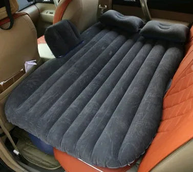 Black inflatable car bed with flocked material and two pillows, set up in a car's rear seats.