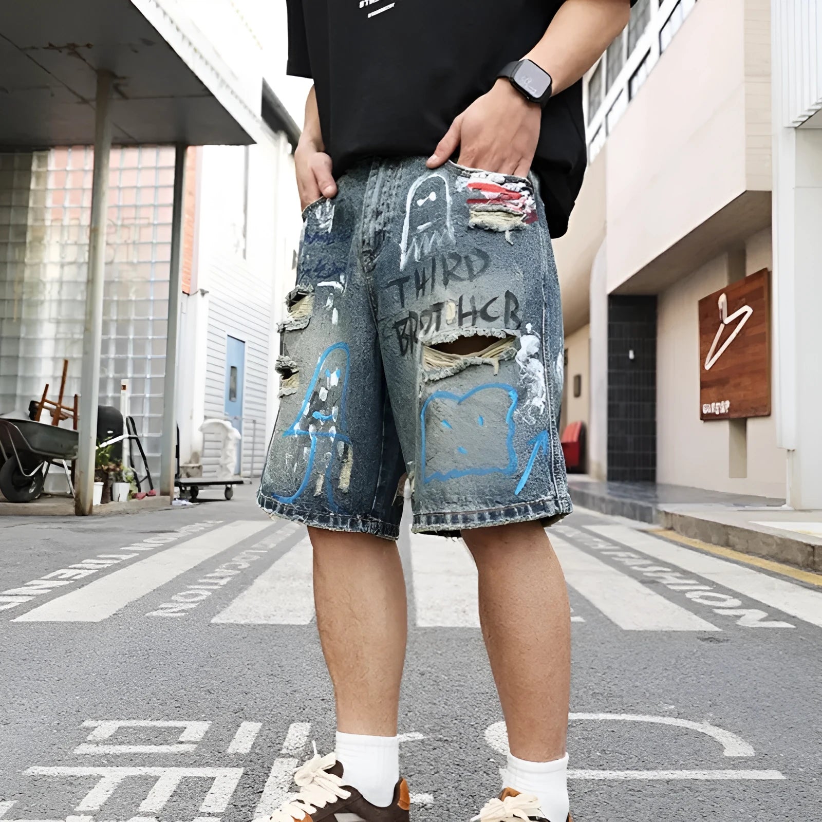 Blue men's ripped denim shorts with graffiti-style detailing and straight-leg cut.