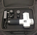 Black and silver deep tissue massage gun with four interchangeable heads on a grey background
