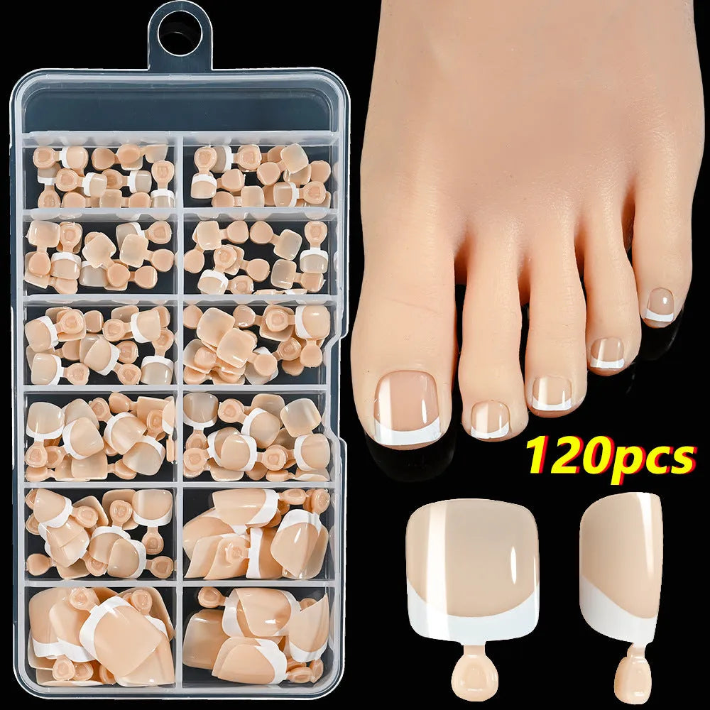 Box of 120 French white edge nude false toe nail pieces in assorted shades on a table