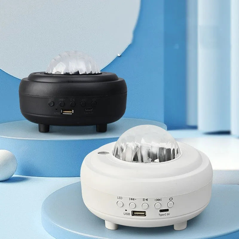 White and black rechargeable galaxy star projector night light with Bluetooth speaker on a table.