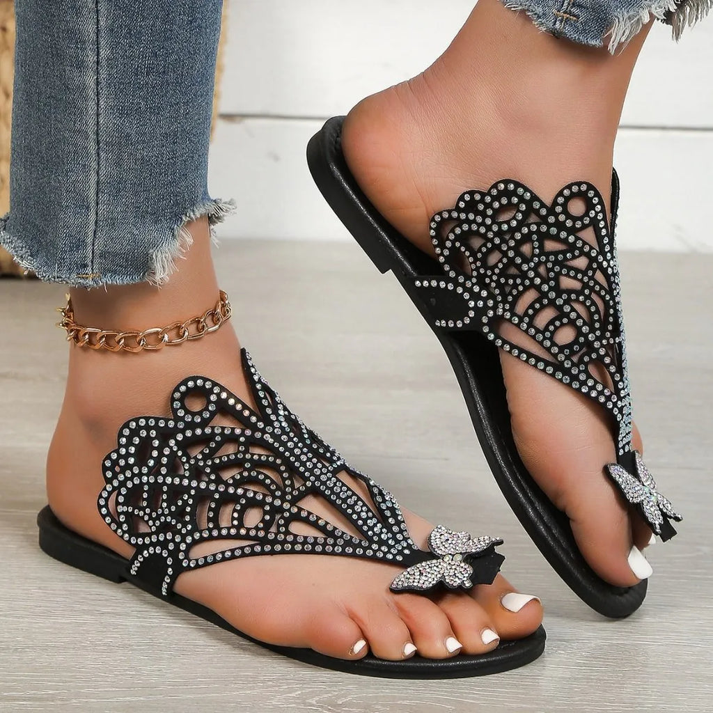 Women's black slip-on sandals with rhinestone decorations and a flat rubber sole.