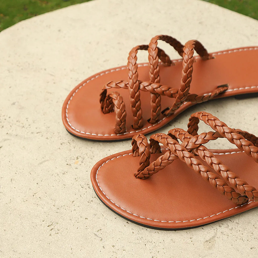 Women's white clip-toe woven flat sandals with a Roman design and rubber sole.