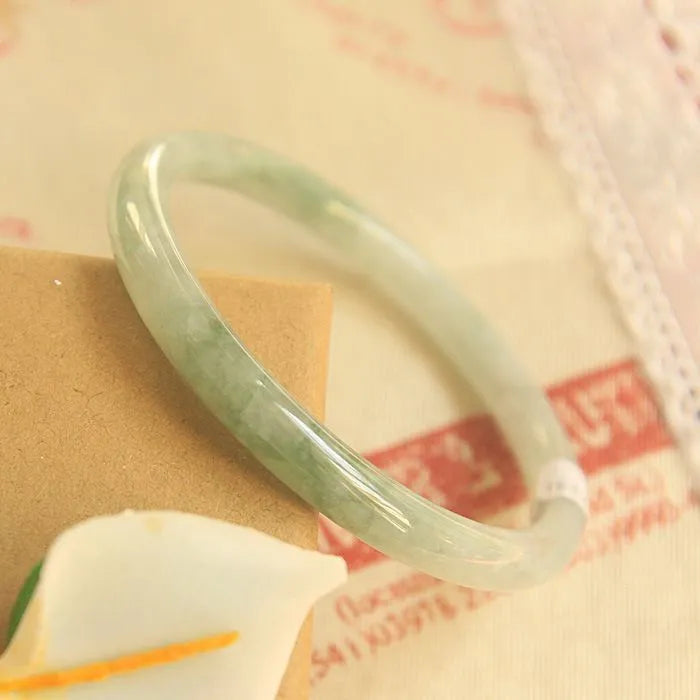 Green jade waxy geometric bracelet with Chinese-style design on a wrist.