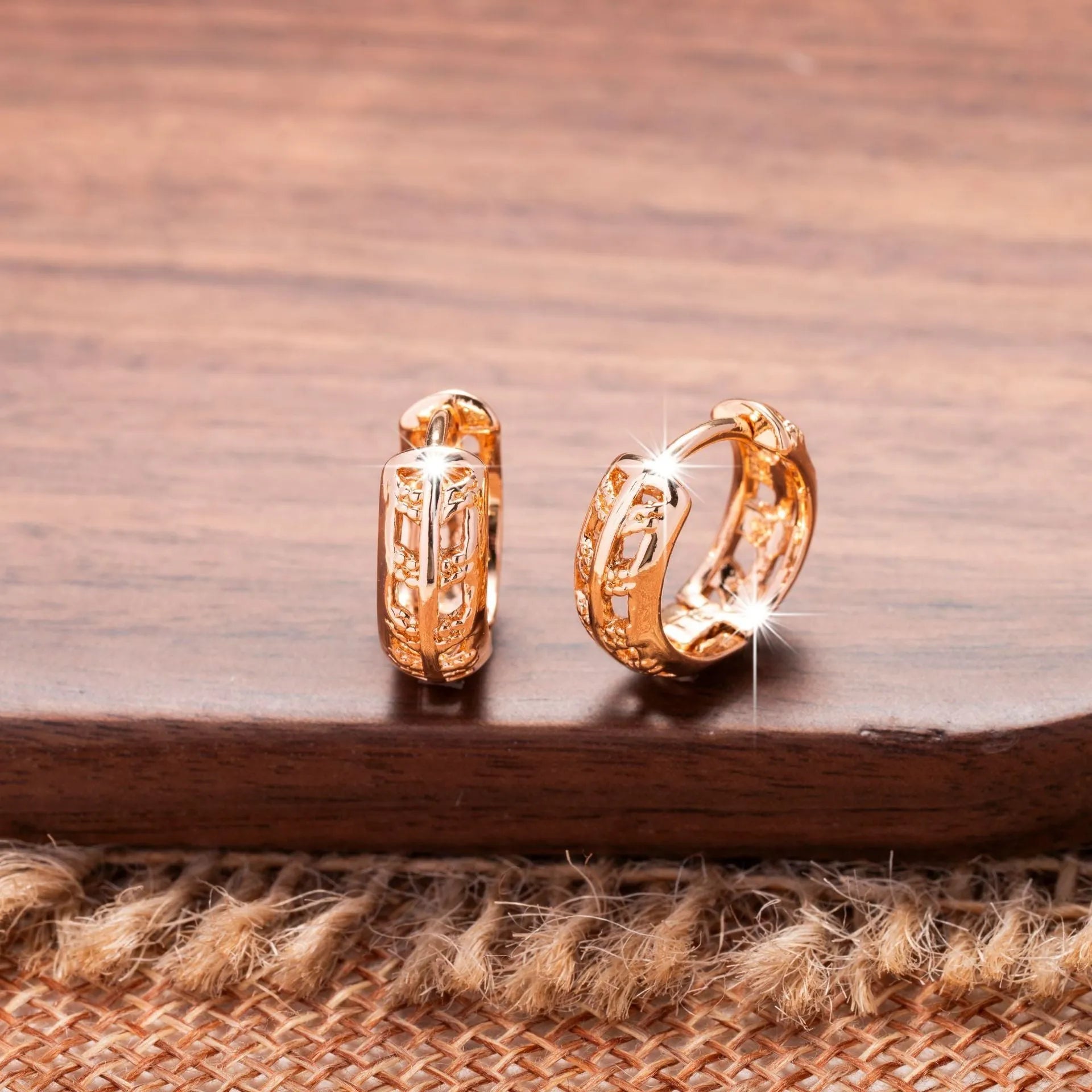 Small rose gold hollowed-out copper earrings with a leaf and a heart pendant design.