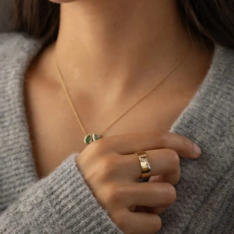 Gold electroplated women's ring with a shining zircon stone, shown on a finger.