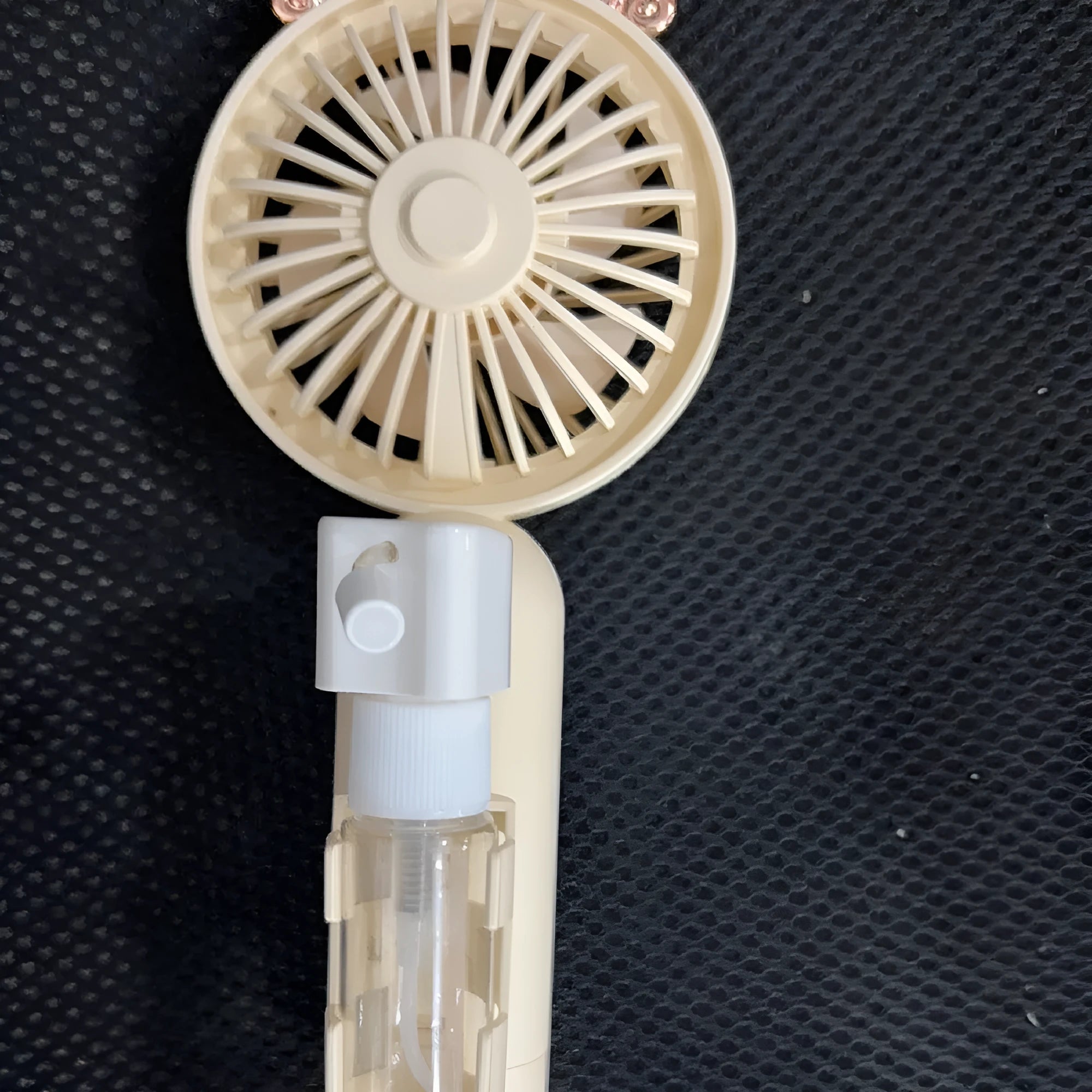 A handheld USB personal fan in one of five colours: apricot, blue, green, orange, or pink, showing its plastic nozzle and compact size.