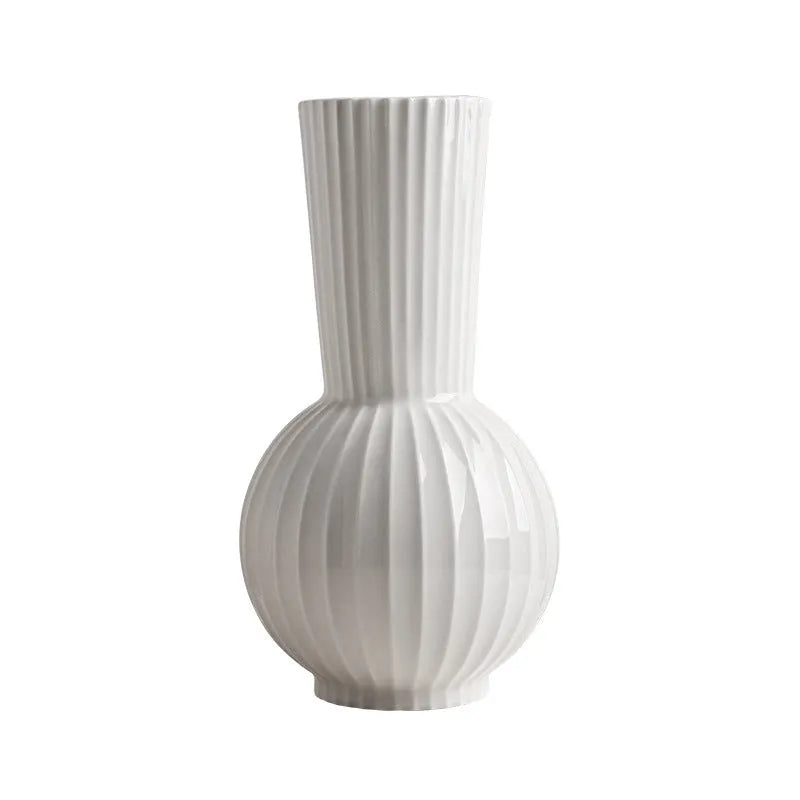White ceramic ball vase with blue stripes and artificial blue orchid flowers on a wooden table.