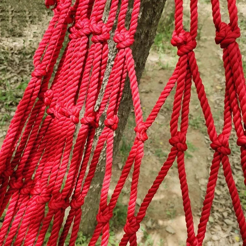 Nylon rope mesh hammock hung between trees showing open weave pattern and included tying ropes