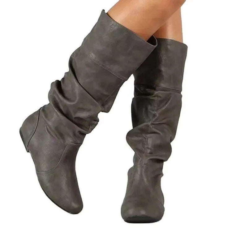 Women's black slip-on long boots with flat heel and round toe on a plain background.