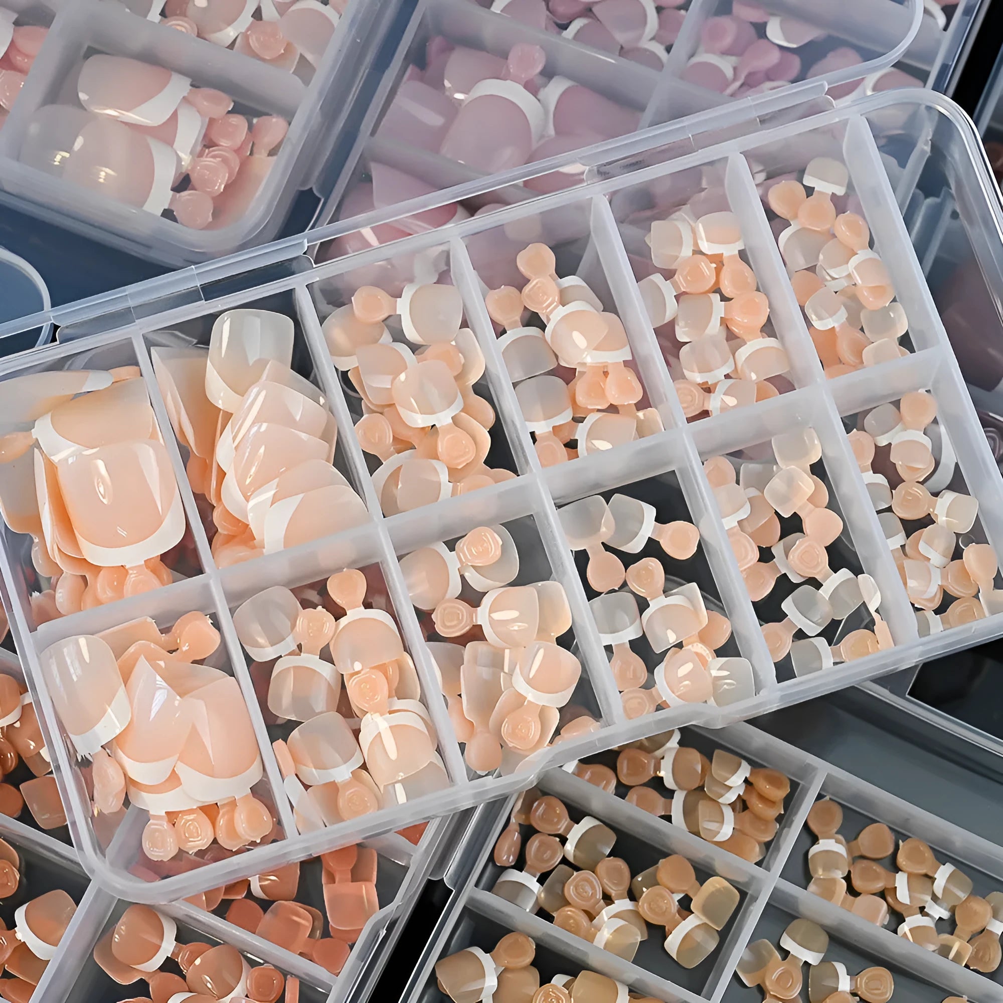 Box of 120 French white edge nude false toe nail pieces in assorted shades on a table