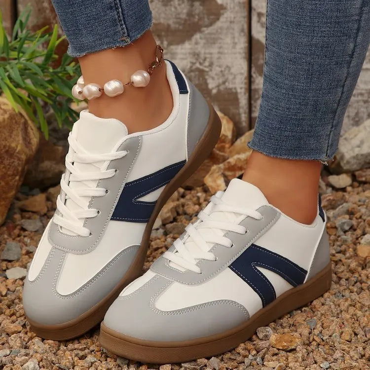 Blue women's low-top hiking shoes with flat rubber sole and lace-up front on artificial grass.