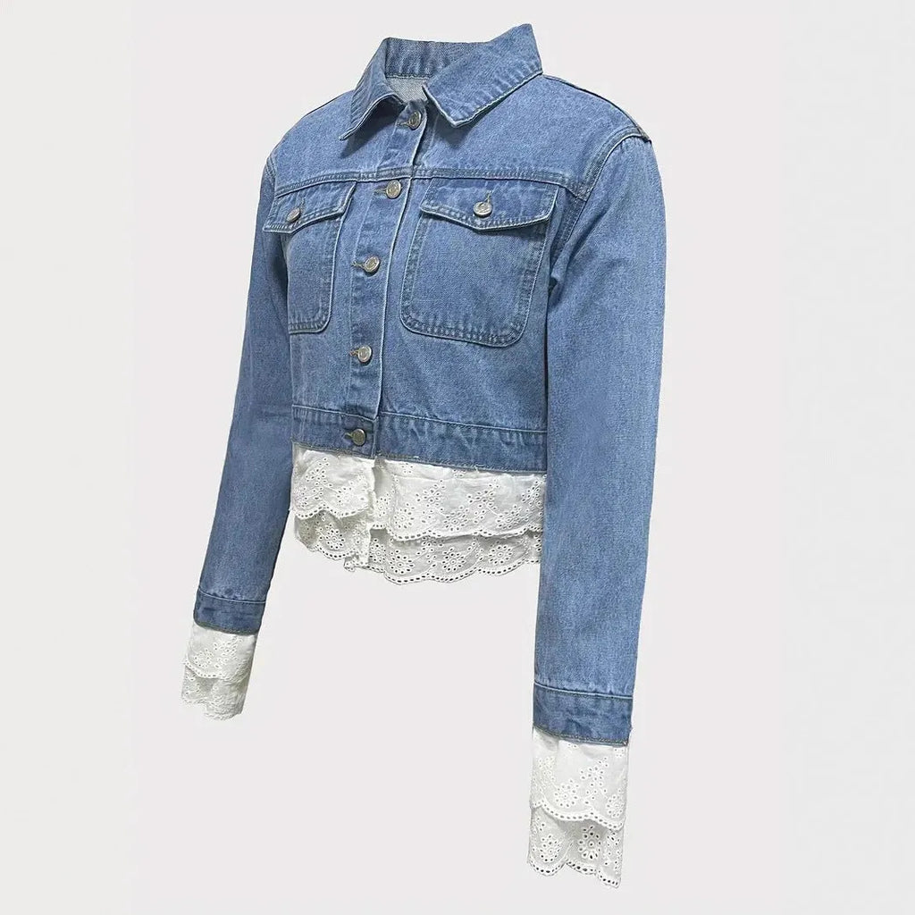 Blue denim jacket for women with lace stitching on the sleeves and front, shown on a hanger.