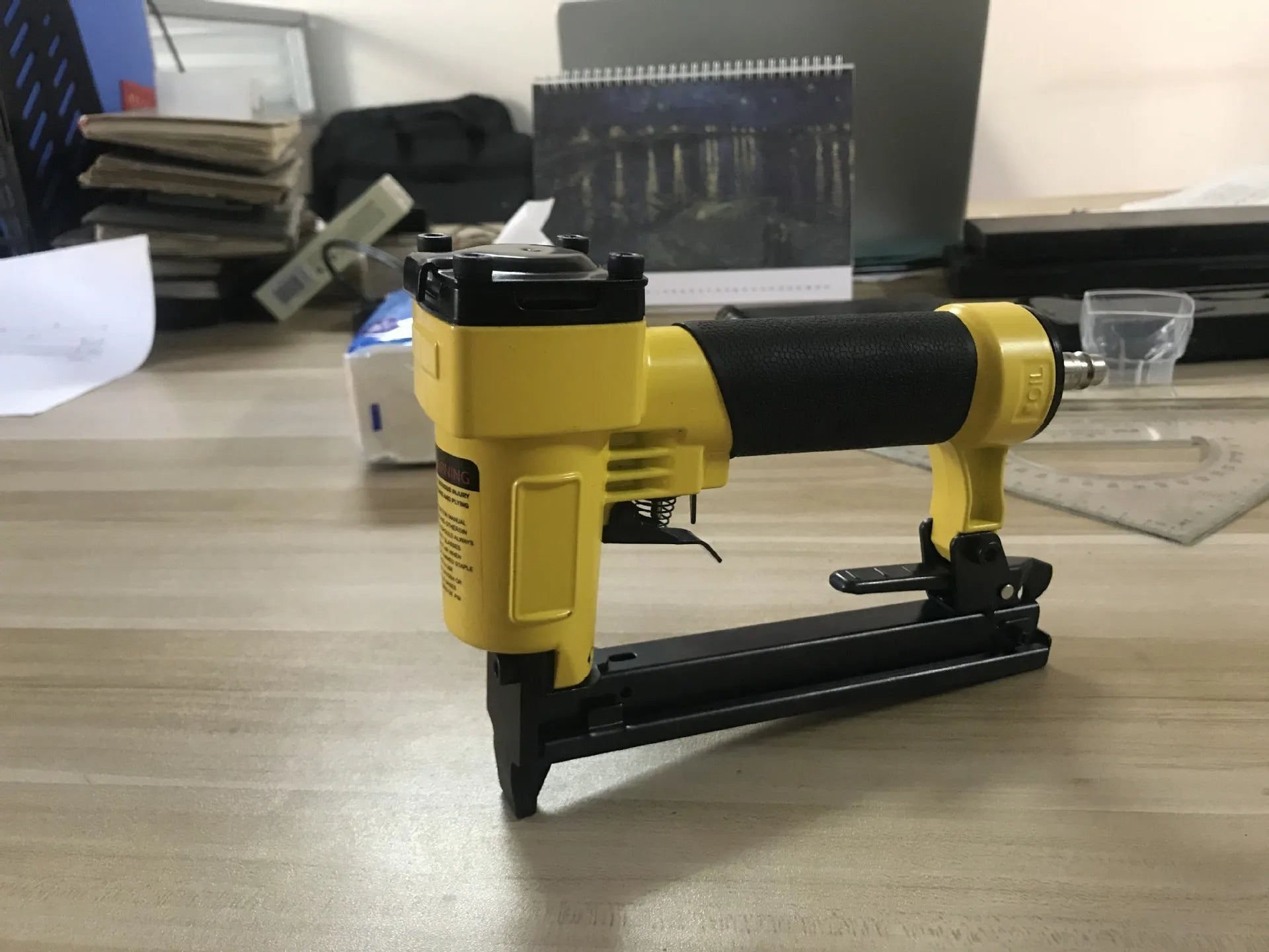 Blue and yellow U-type pneumatic strip nail gun for interior decoration and furniture work.