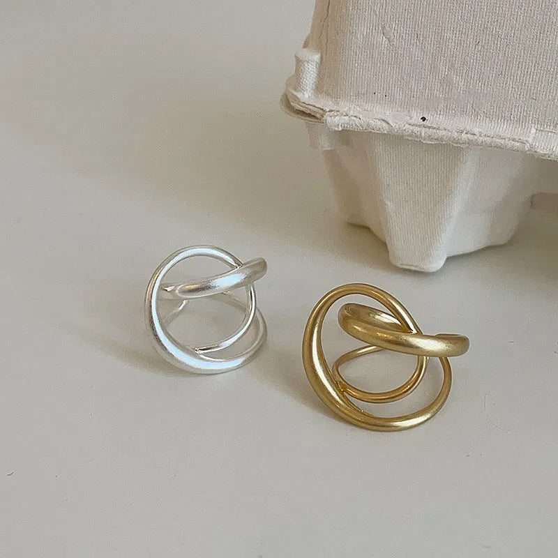 Geometric interlaced open ring with a matte metal finish in gold tone plating.