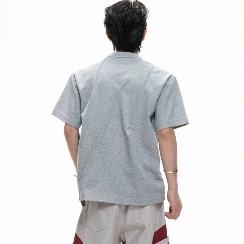 Man modelling a loose grey cotton T-shirt with a round neck and asymmetric stitching detail on the front.