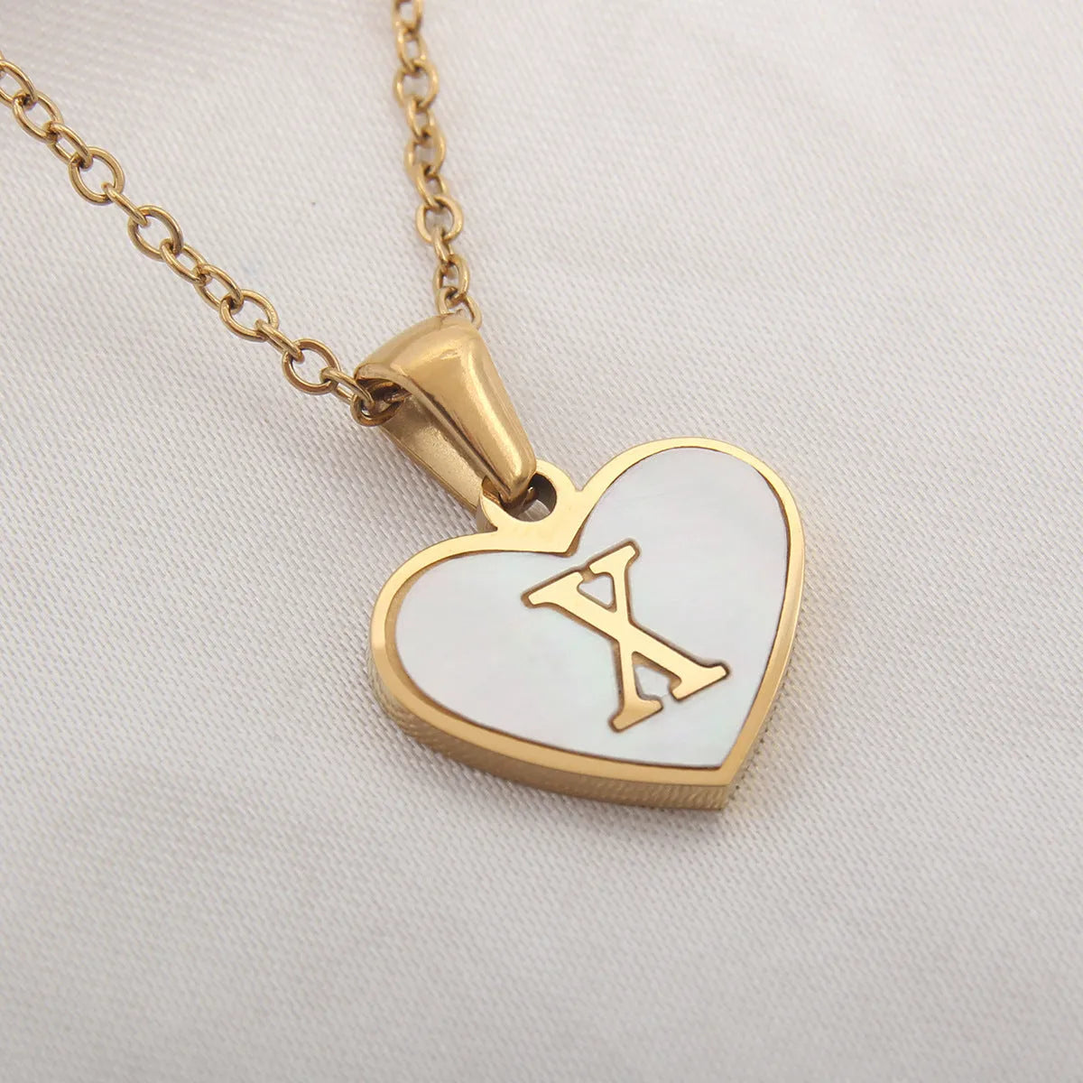Gold heart necklace with white shell detail and personalised initial letter on adjustable chain