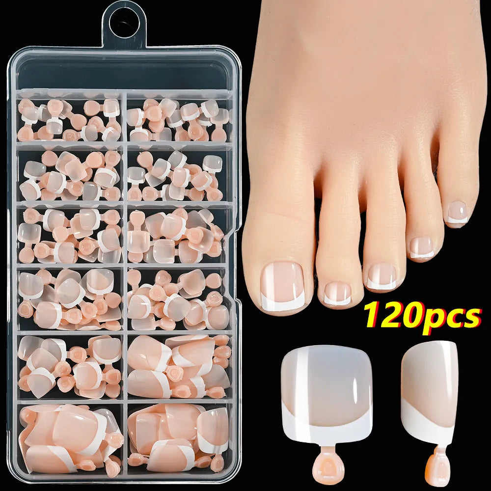 Box of 120 French white edge nude false toe nail pieces in assorted shades on a table