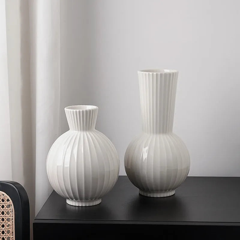 White ceramic ball vase with blue stripes and artificial blue orchid flowers on a wooden table.