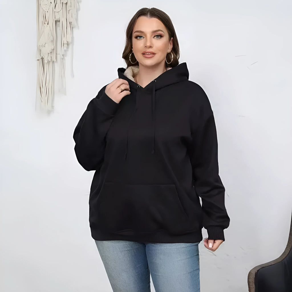 A woman wearing a loose thick black hooded sweater with side pockets and a 3D textured pattern.