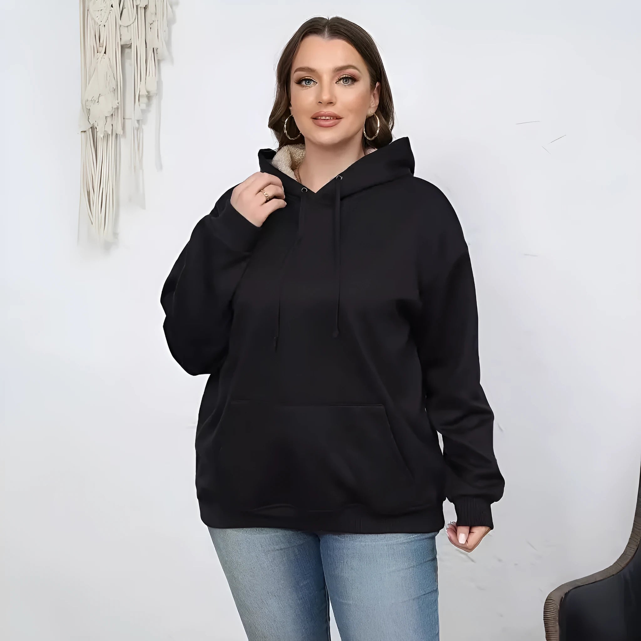 A woman wearing a loose thick black hooded sweater with side pockets and a 3D textured pattern.