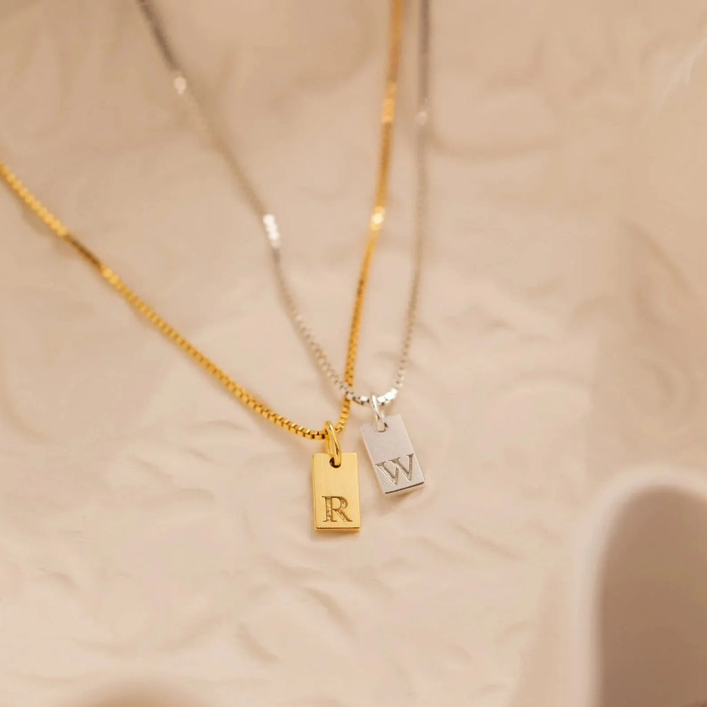 Mini square stainless steel initial necklace with gold plating on a sparkling box chain