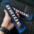 Pair of black cotton seat belt shoulder sleeves with embroidery, shown next to a car seat.