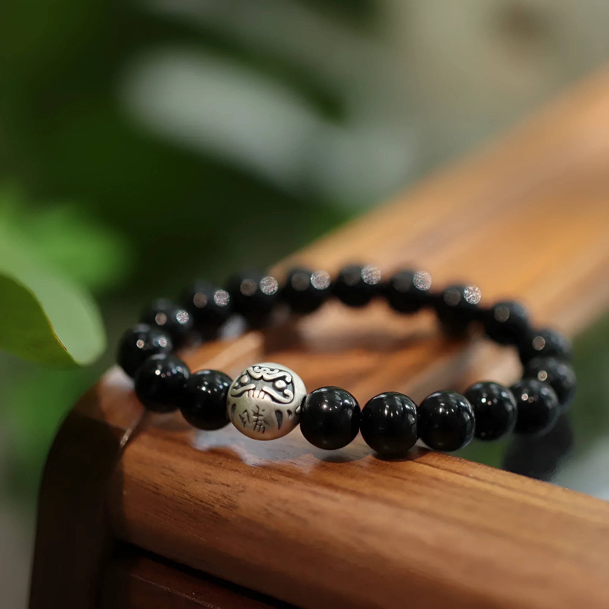 Close-up of a bracelet with large round black agate beads and a sterling silver clasp on a wrist.