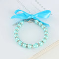Small dog wearing adjustable pearl and rhinestone necklace with soft ribbon bow in blue colour