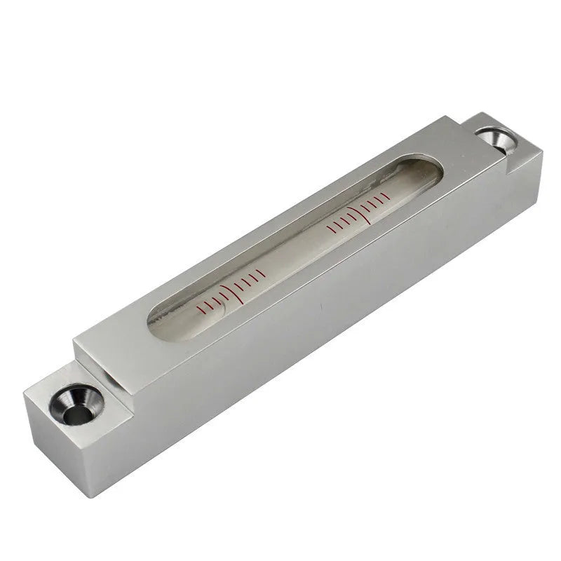 Small silver metal spirit level with glass vials on a workshop bench