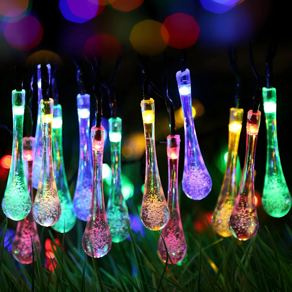 Solar-powered LED outdoor string lights with bubble drop pendants decorating a garden fence