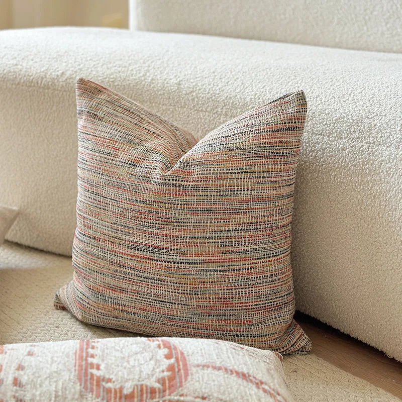 American-style jacquard cushion cover with paisley and flower pattern in amber colours on a sofa.