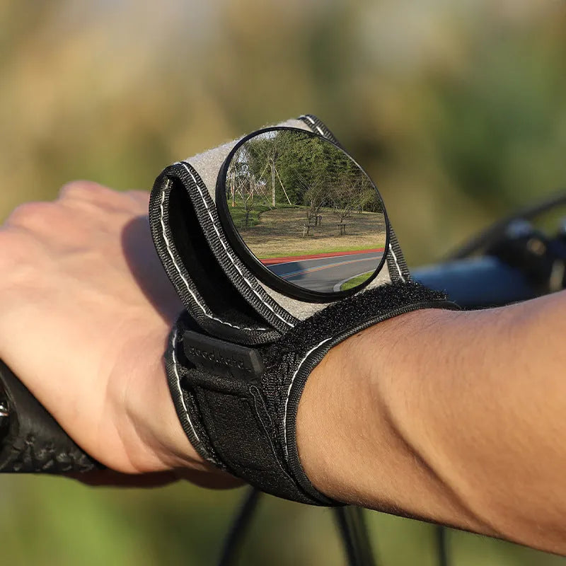 Black nylon wrist-mounted rear-view mirror for bicycles on a cyclist's wrist.