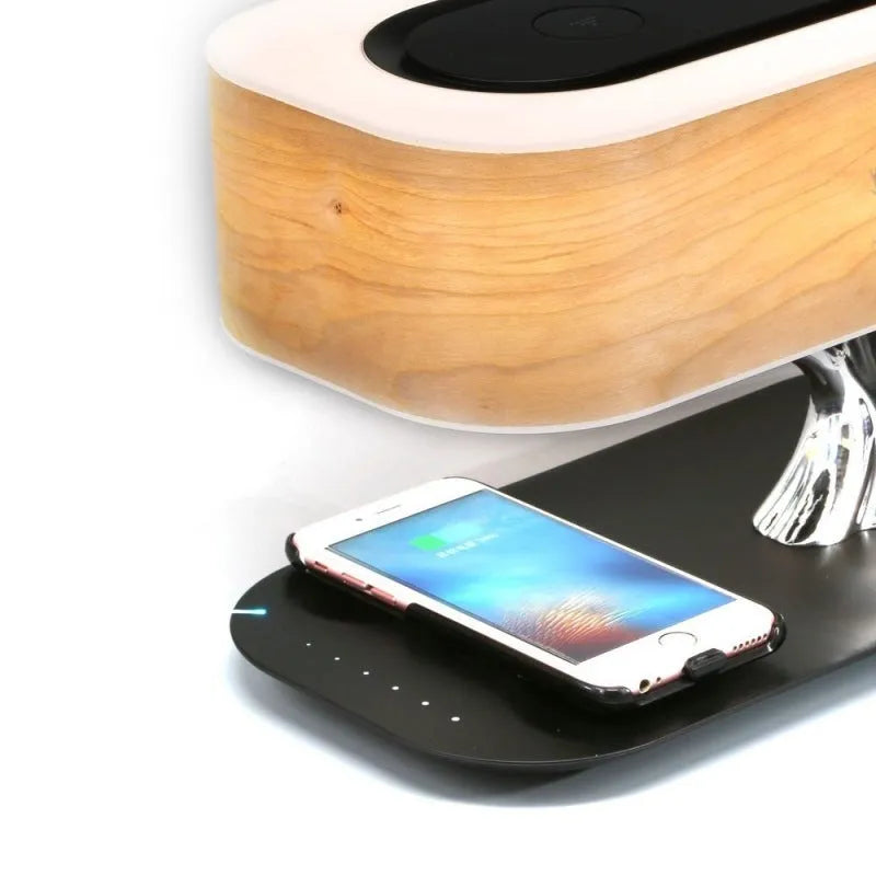 Creative tree light table lamp with natural cherry veneer shade, Bluetooth speaker, and wireless charging on a bedside table