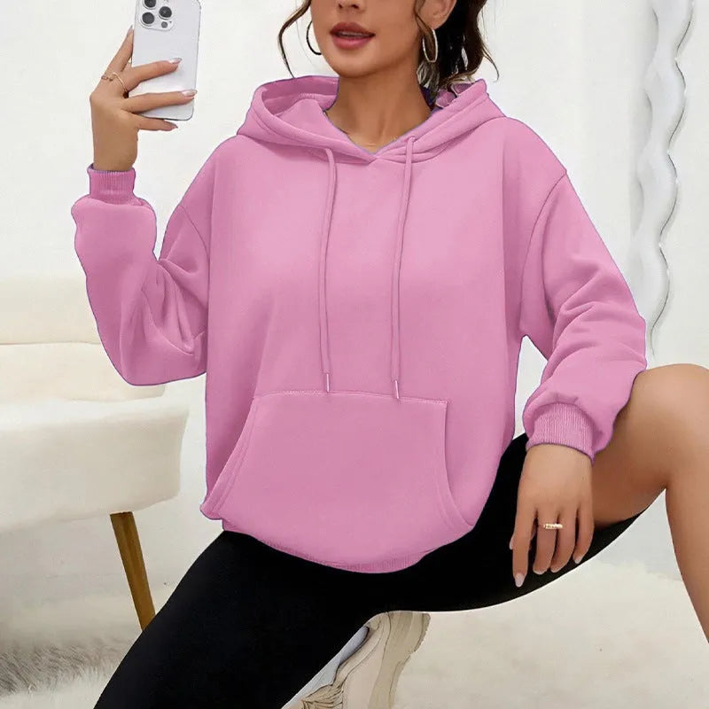 Woman wearing a loose grey drawstring waist sweatshirt with front pockets and long sleeves.