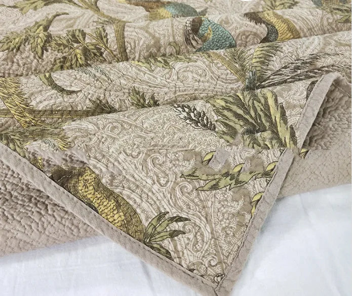 Blue American floral and bird pattern quilted cotton bedspread set of three pieces on a bed.