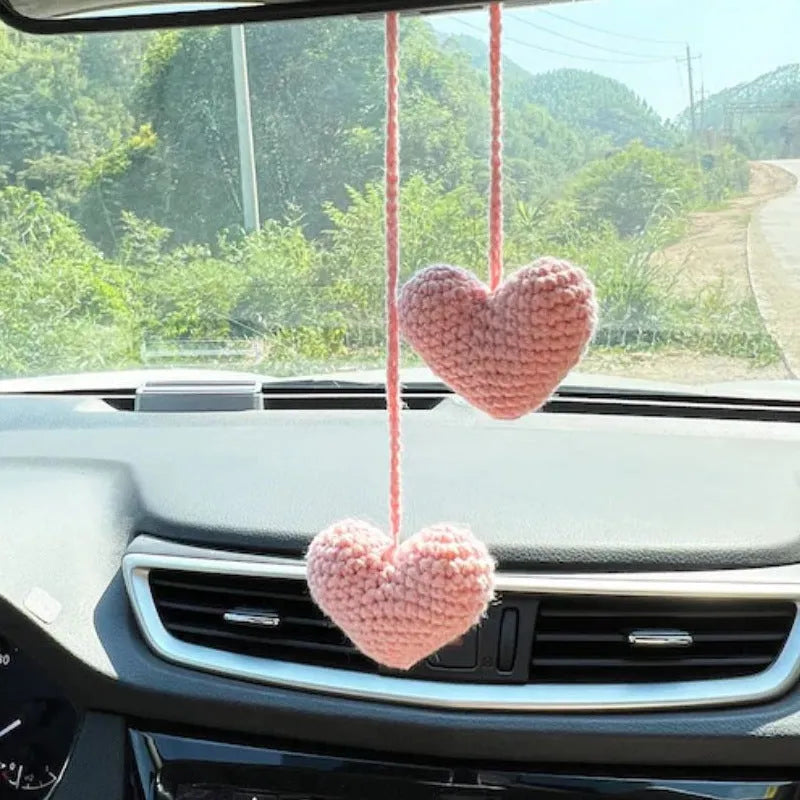 Green and white knitted wool car plant decoration with hanging rope on a car dashboard