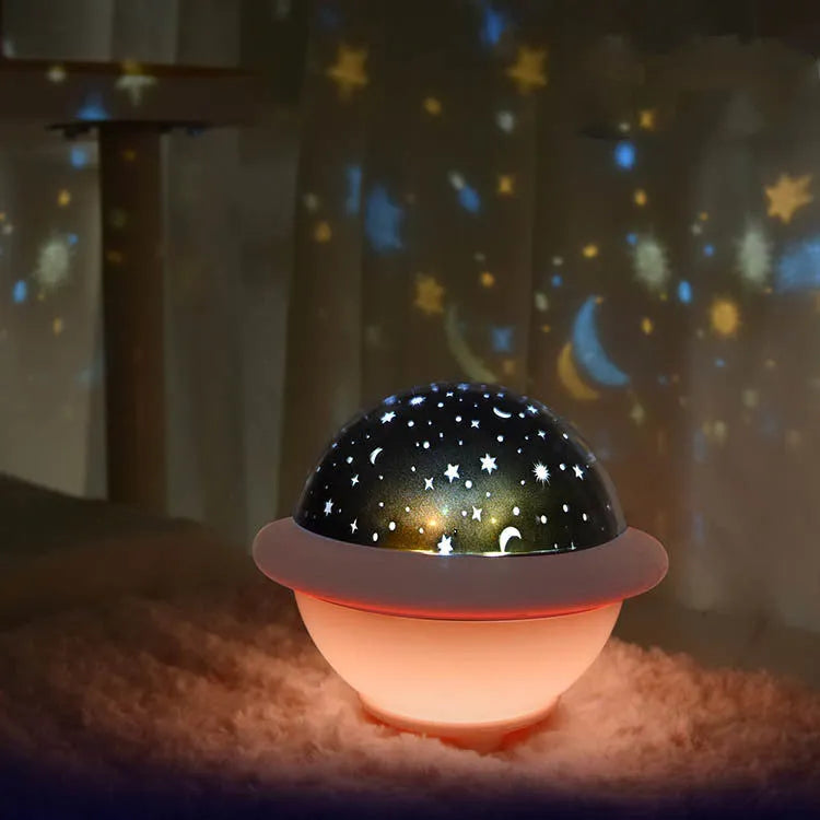 UFO-shaped plastic starry sky projection night light in pink on a wooden surface
