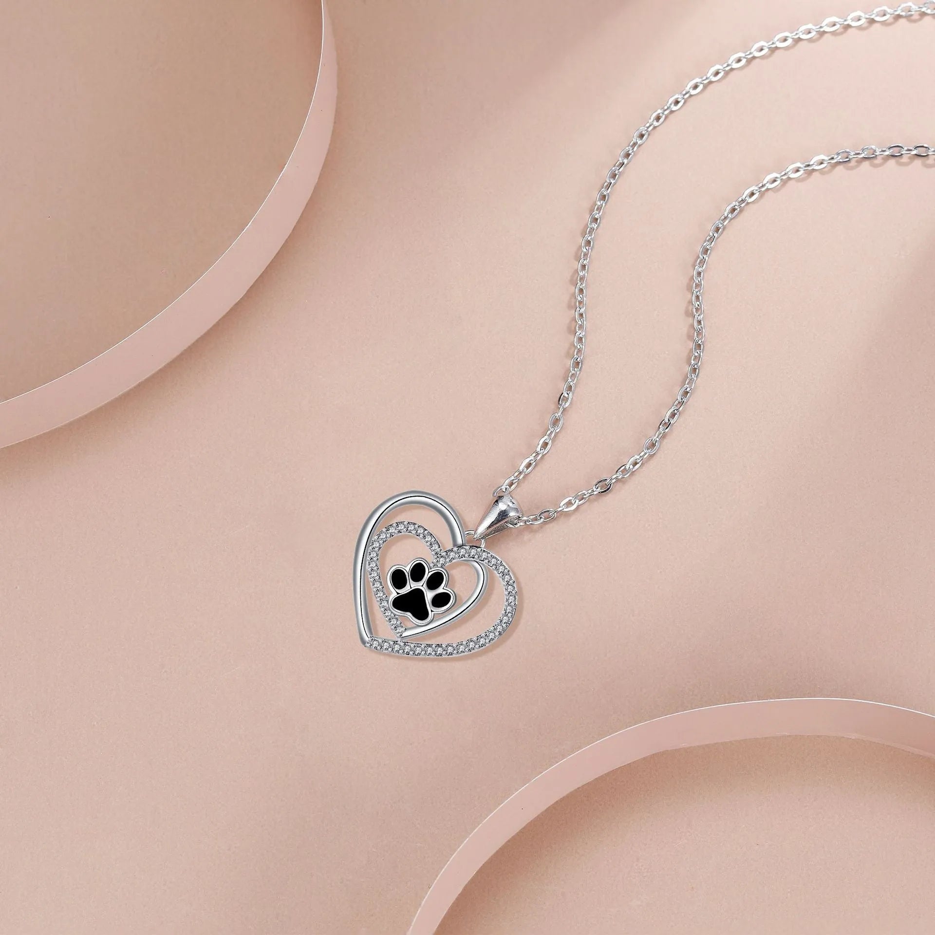 Women's dog paw print necklace with heart-shaped pendant on a cross chain.