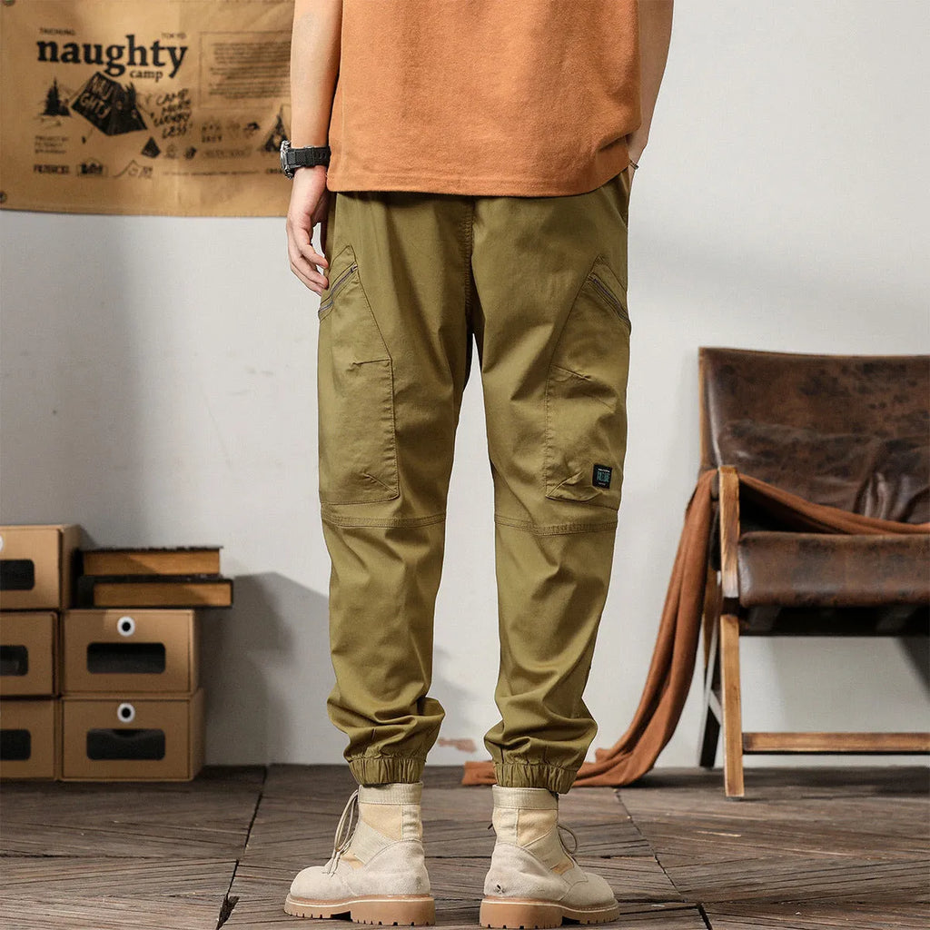 Men's khaki cotton harem pants with tapered ankle bands and a mid-waist zip fly.