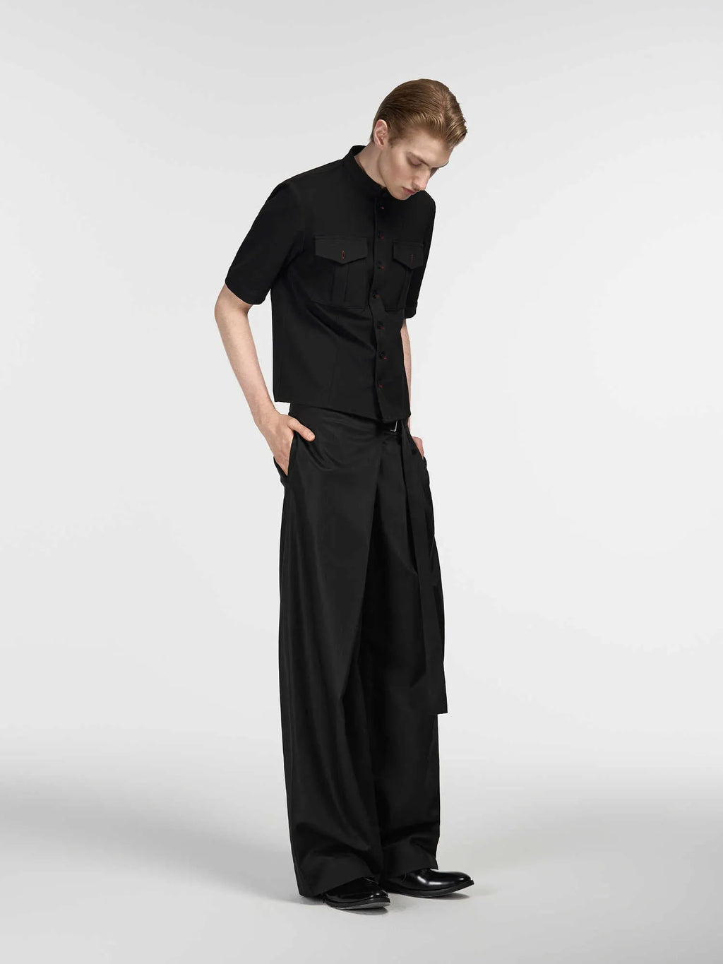 Black straight-leg trousers with a single front pleat and adjustable waistband, laid flat.