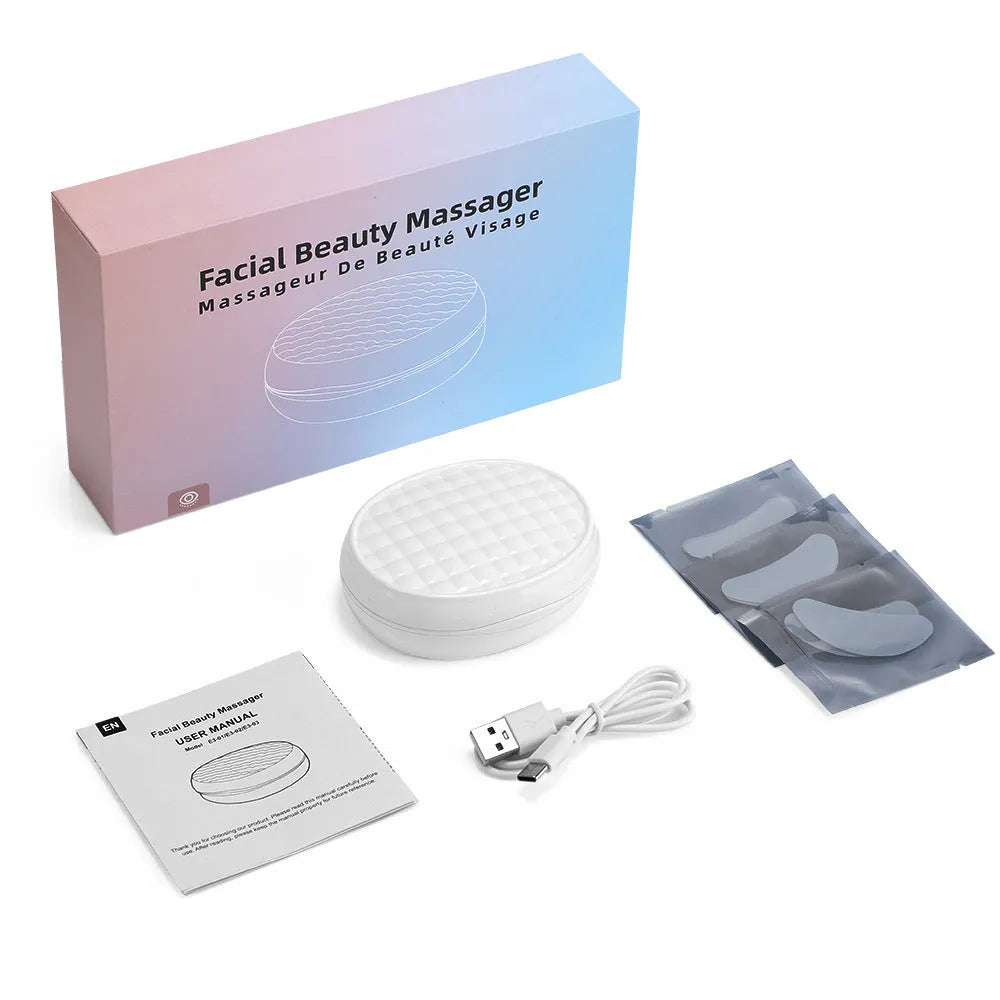 White wireless red light EMS eye and facial massager device on a table
