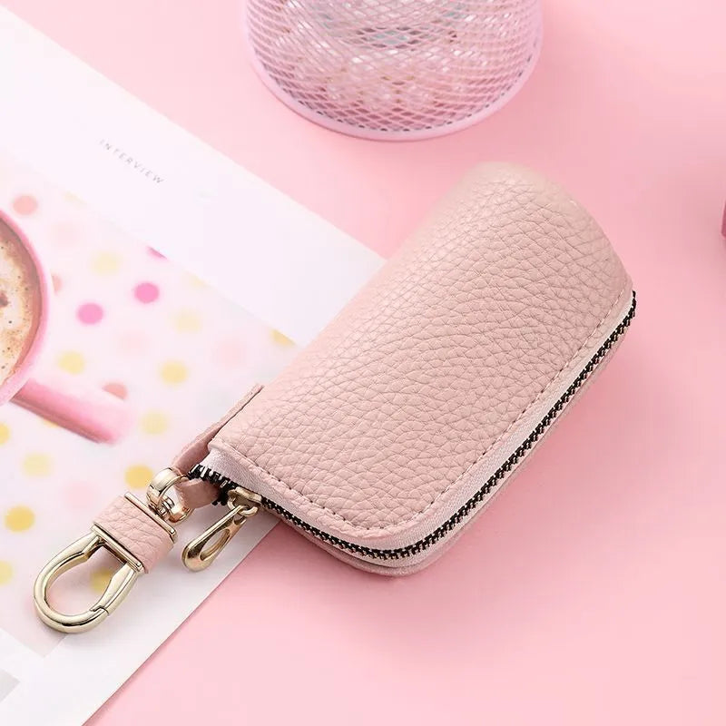 Simple black PU leather zipper key ring case on a grey background.