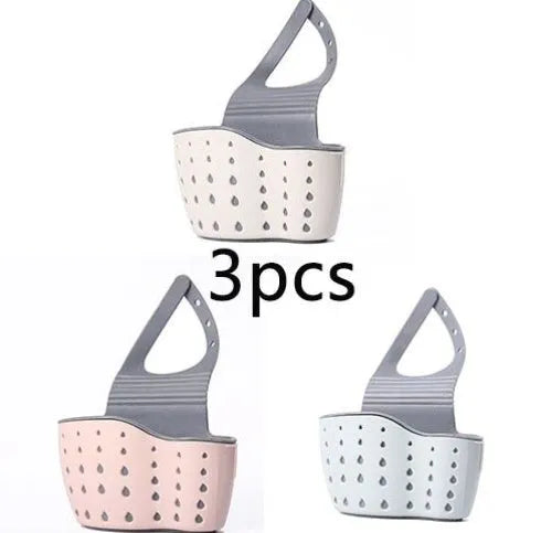 Set of three plastic kitchen sink storage racks in light blue, light pink, and beige on a countertop