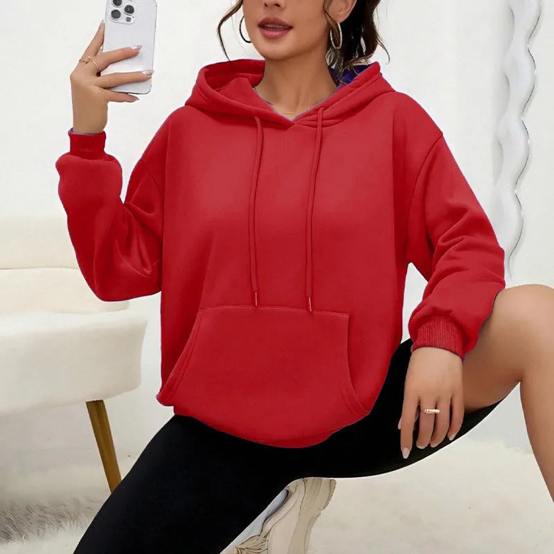 Woman wearing a loose grey drawstring waist sweatshirt with front pockets and long sleeves.