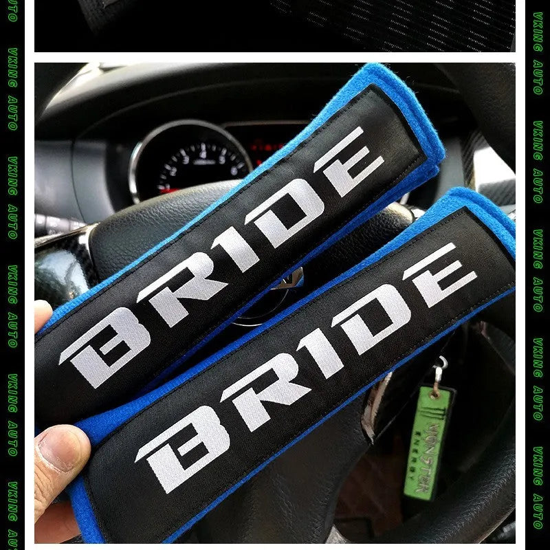 Pair of black cotton seat belt shoulder sleeves with embroidery, shown next to a car seat.
