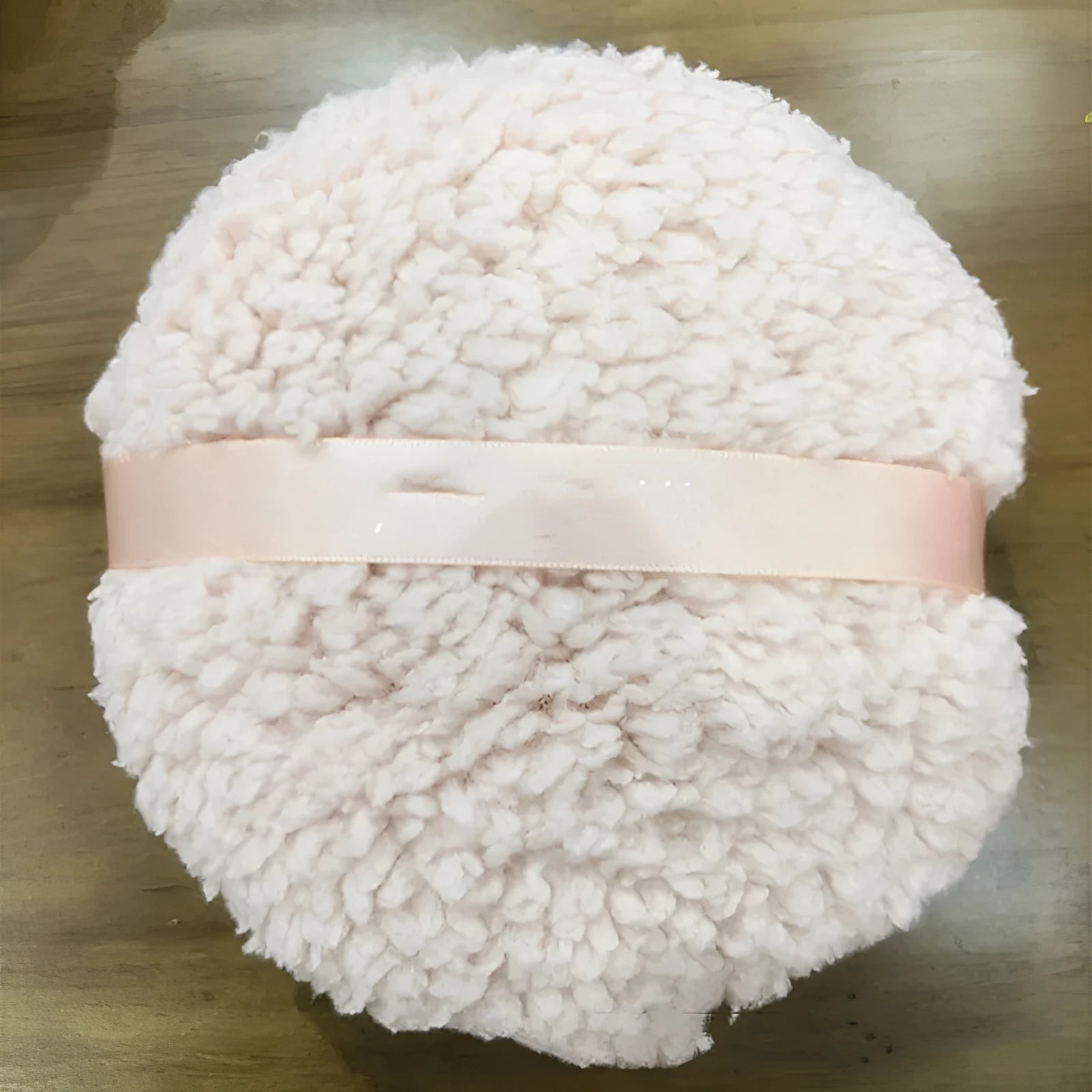 Oversized soft plush makeup powder puff in pink, white, and skin colour on a white background