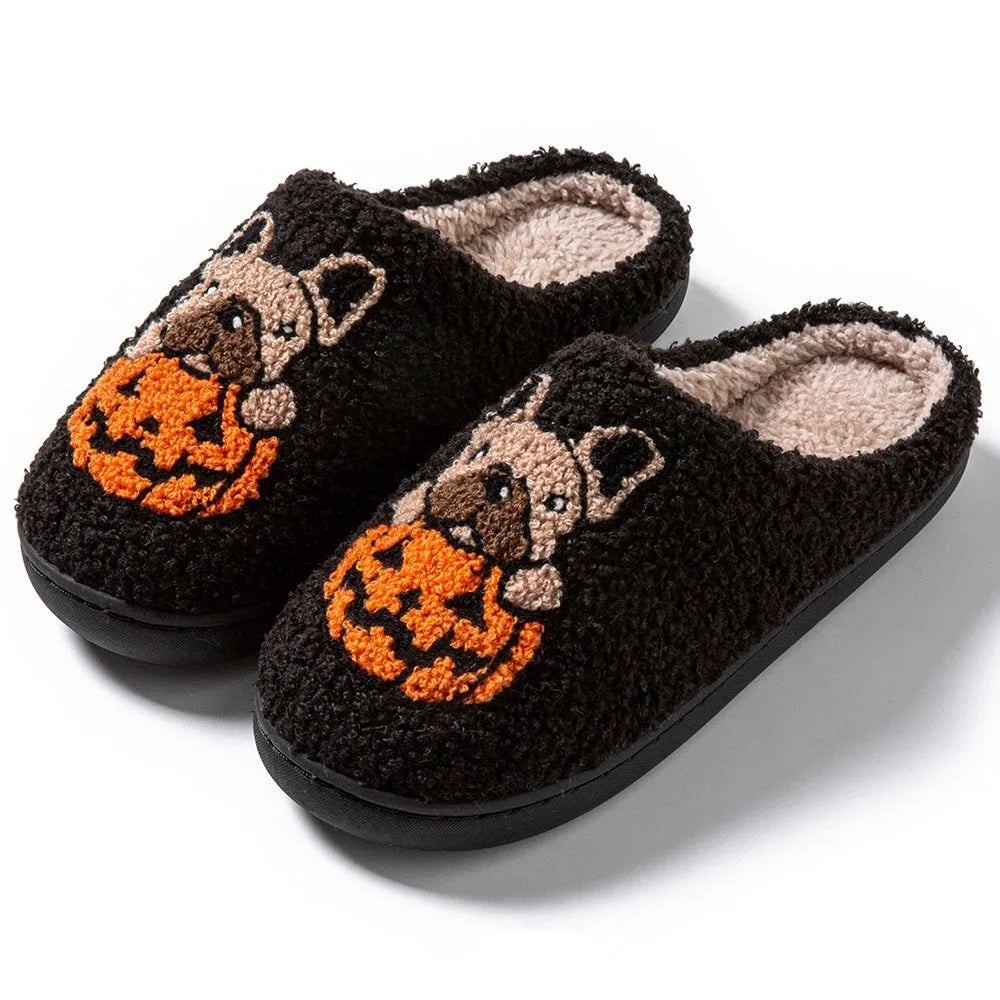 Black and white Halloween pumpkin plush slippers with non-slip rubber soles on a wooden floor