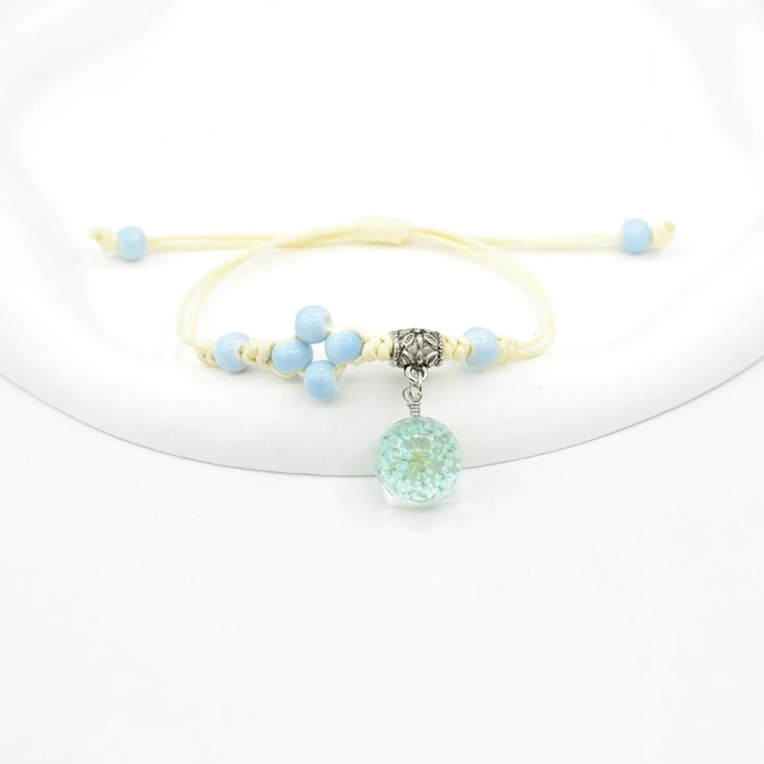 Glass bracelet with large colourful beads containing real dried flowers, on a white background.